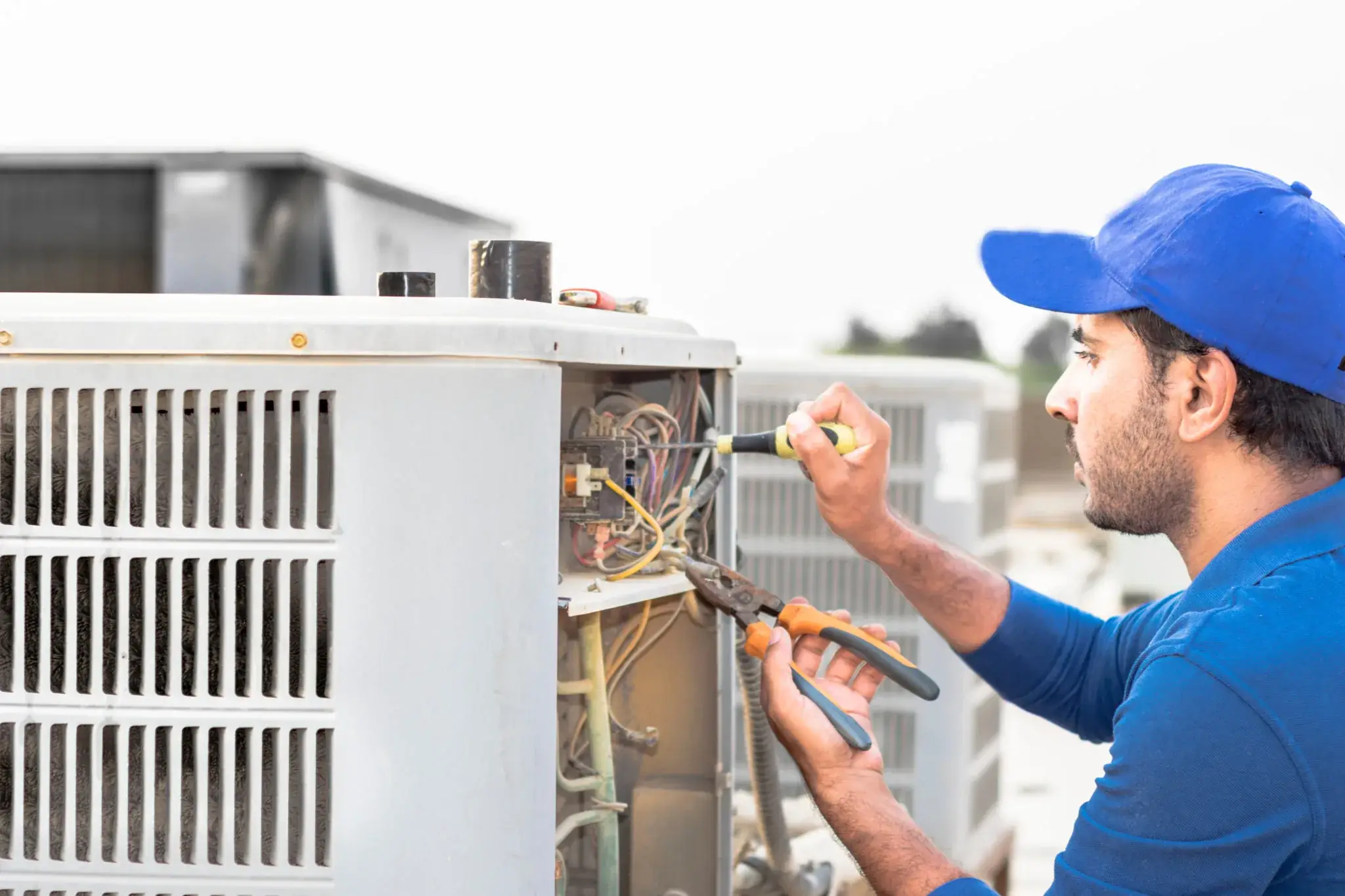 AC technician repairing the electrical wiring of an outdoor condenser unit on a rooftop, AC repair and maintenance services in Dubai by Limech
