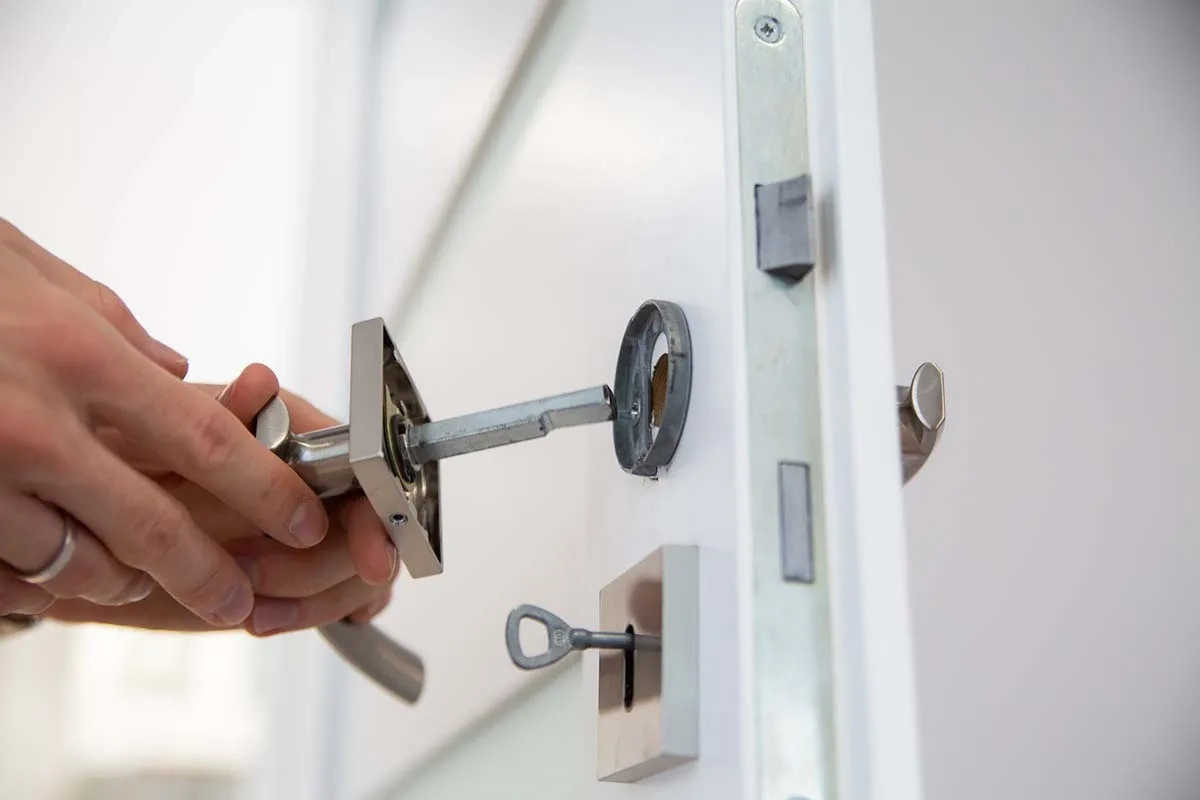 Technician installing a door handle and mortise lock on a white door, door lock repair and installation services in Dubai by Limech
