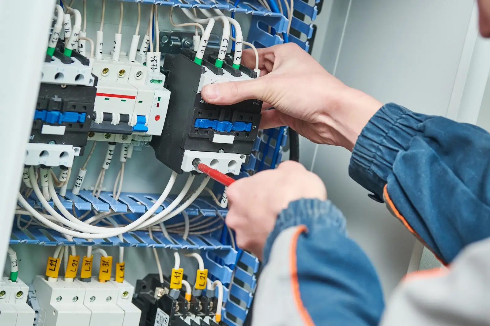 Electrician repairing a contactor in an electrical control panel, electrical maintenance services in Dubai by Limech