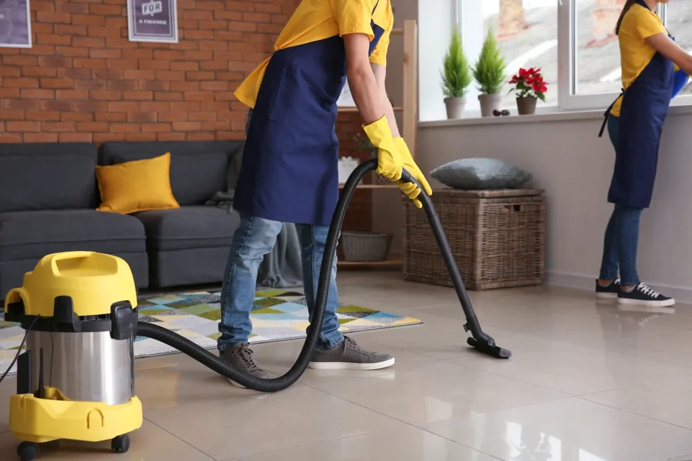Cleaners vacuuming the floor and cleaning windows in a living room, professional home cleaning services in Dubai by Limech